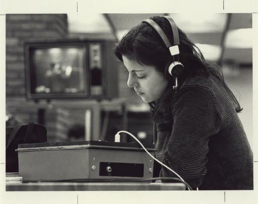 Female student in library with headphones and monitor; REACH class