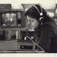 Female student in library with headphones and monitor; REACH class